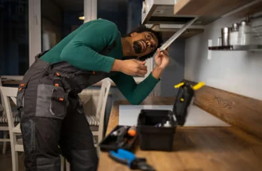 Handyman fitting under a kitchen worktop